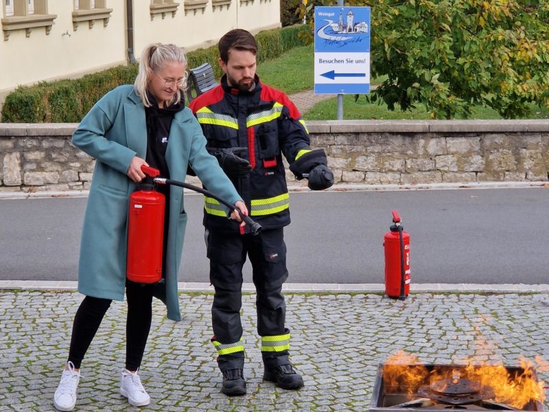 Ein Mitarbeiter der Johanniter zeigt einer Mitarbeiterin von eology, wie man richtig löscht